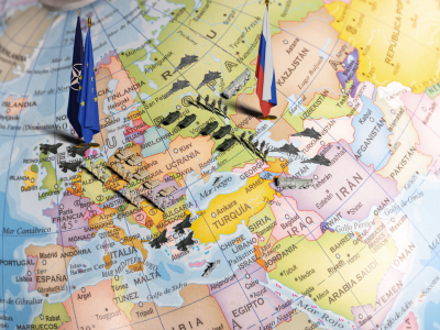 Close up on a world map with pins and miniature flags representing geopolitical landscape