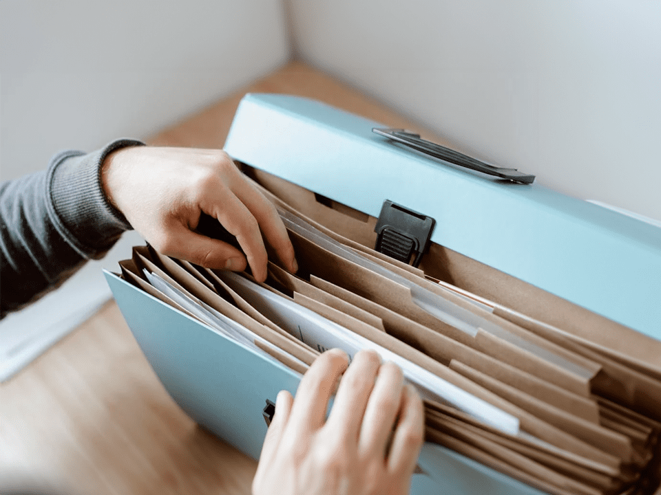 Two hands searching through a paperwork folder