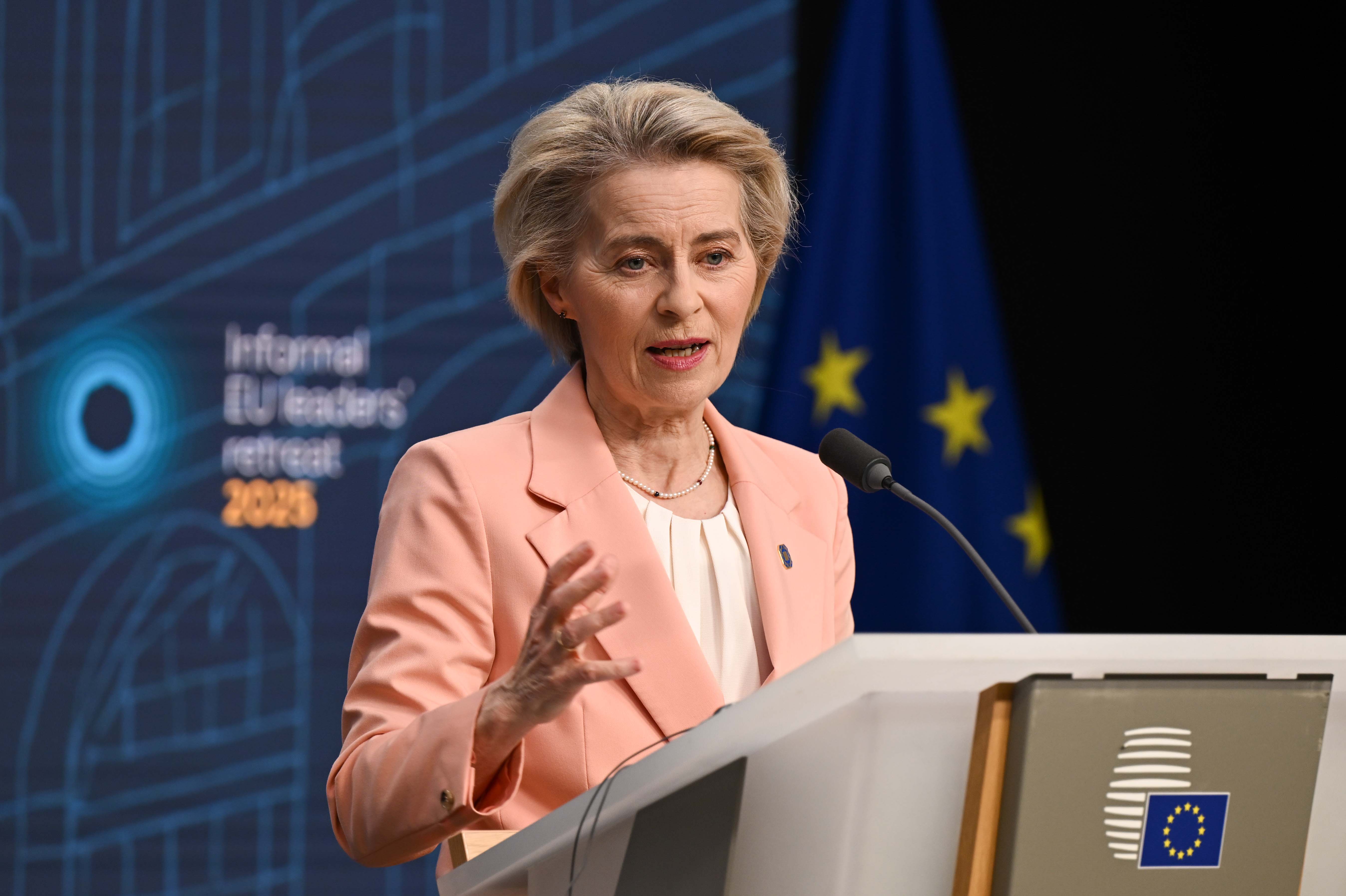 The EU president Ursula von der Leyen is standing in a blazer holding speech.