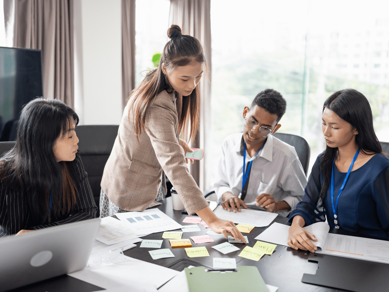 Four people sat at a desk, overlooking paperwork, three woman and one male