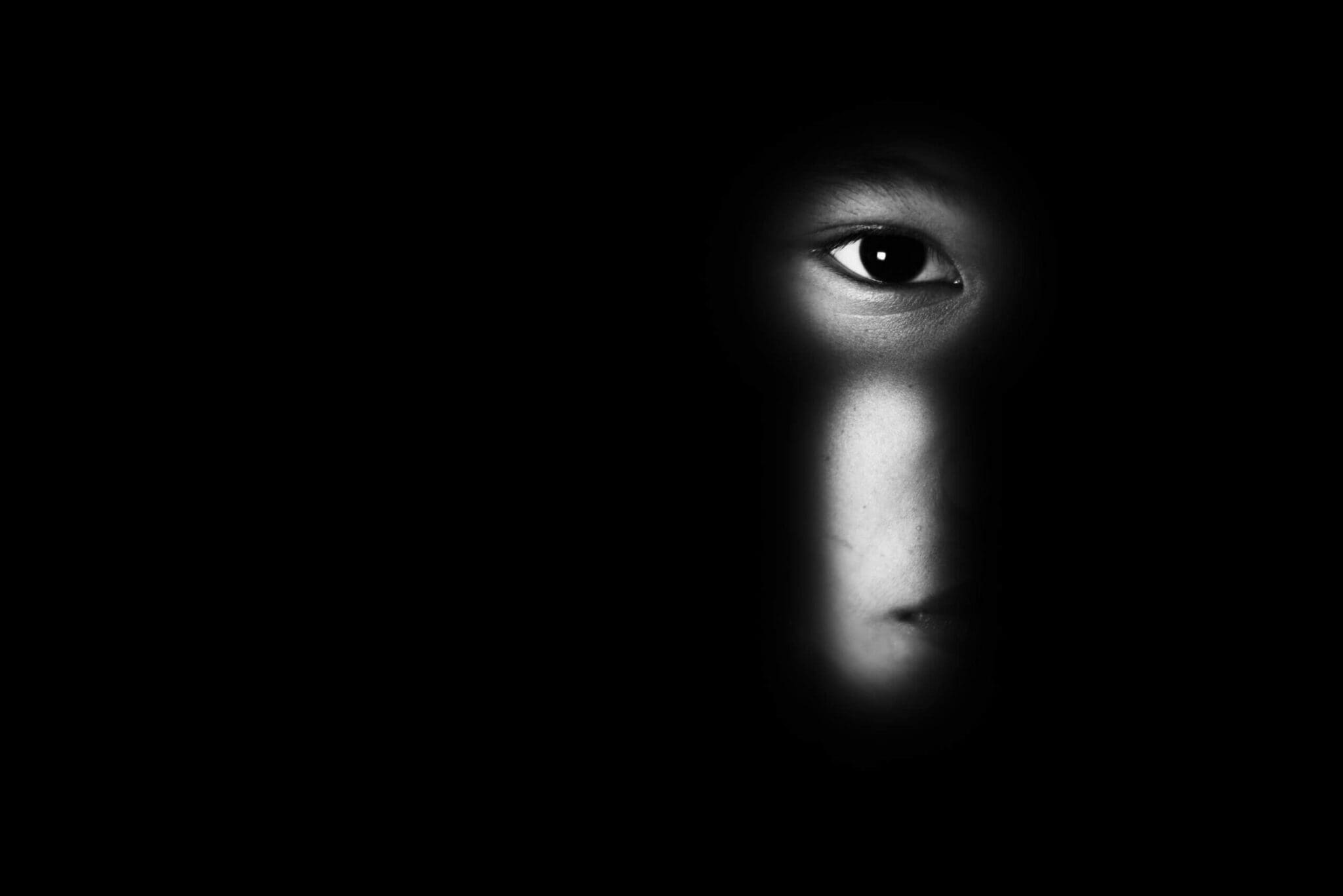 Partially concealed face in darkness, representing the hidden human impact of modern slavery in Australian supply chains.