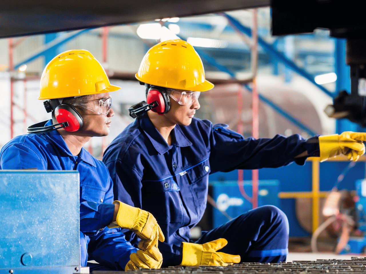 Workers in a factory wearing hard hats and goggles